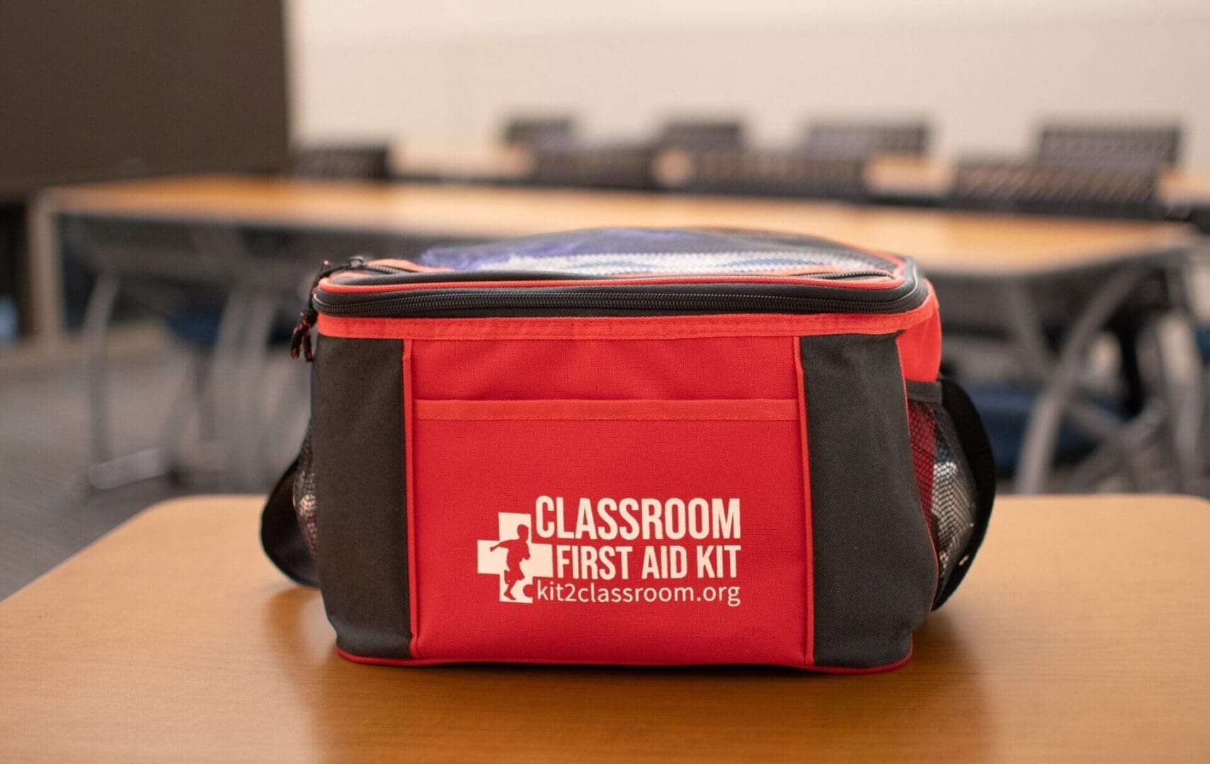 A red and black first aid kit sitting on top of a table.